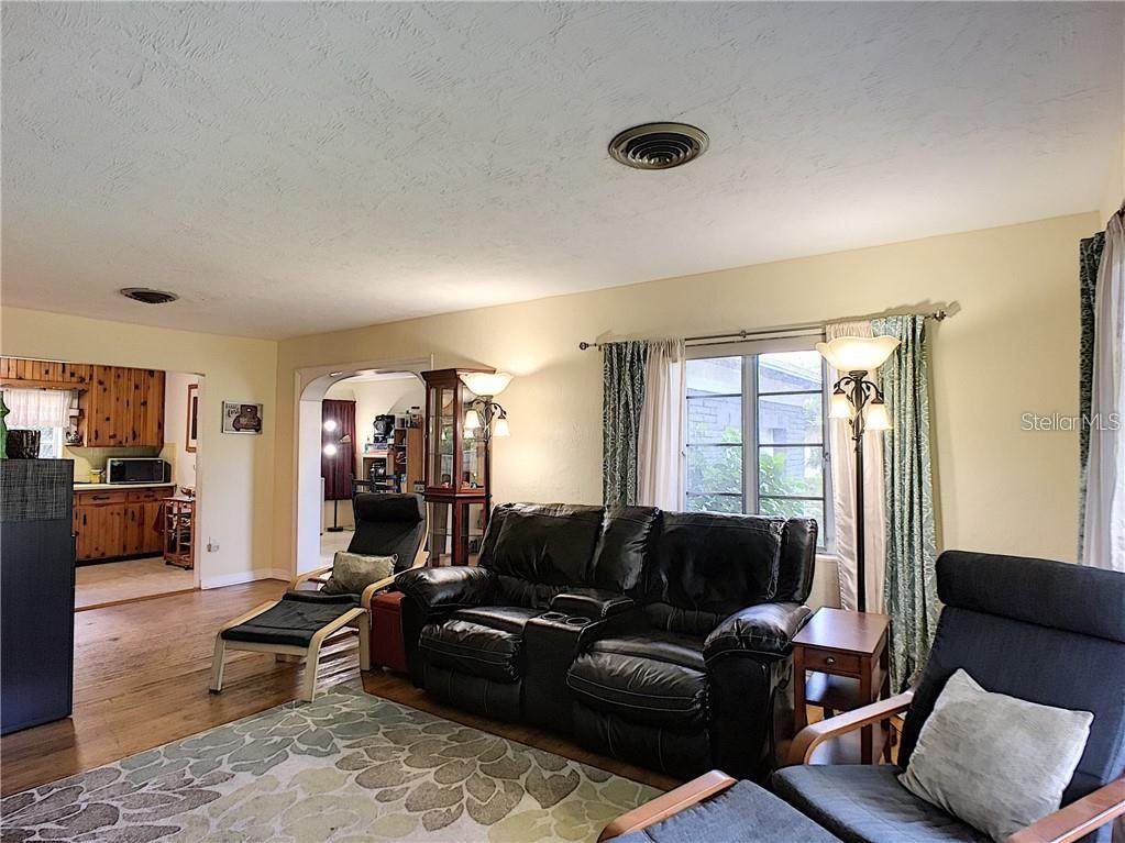 A living room with a black leather sofa, two armchairs, and a view into the kitchen — 503 KILSHORE LANE, WINTER PARK, FL