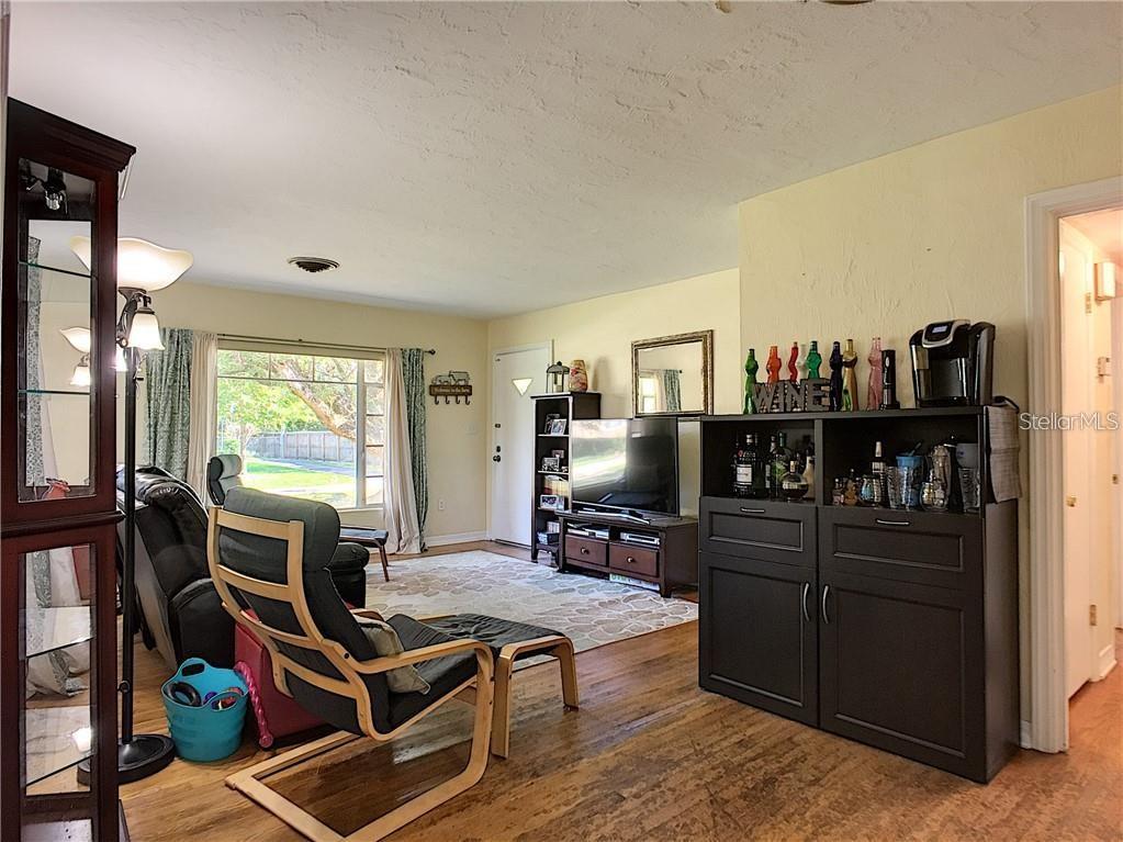 A living room features hardwood floors, a television console, a bar cabinet, and a window — 503 KILSHORE LANE, WINTER PARK, FL