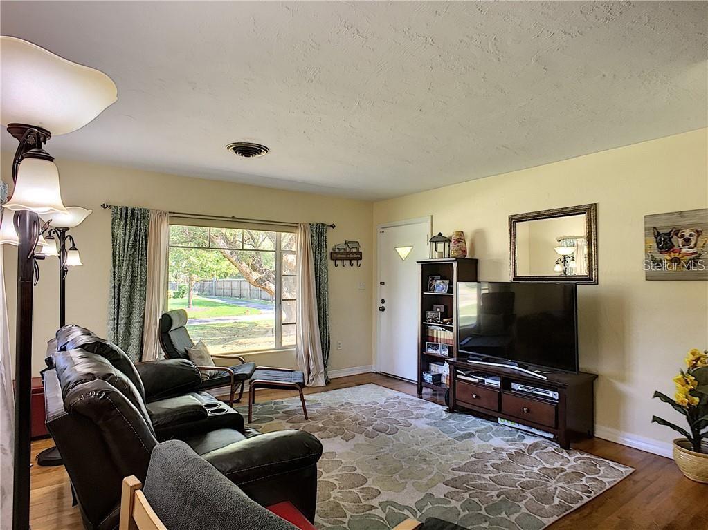A living room with a leather sofa, television, area rug, and a large window — 503 KILSHORE LANE, WINTER PARK, FL