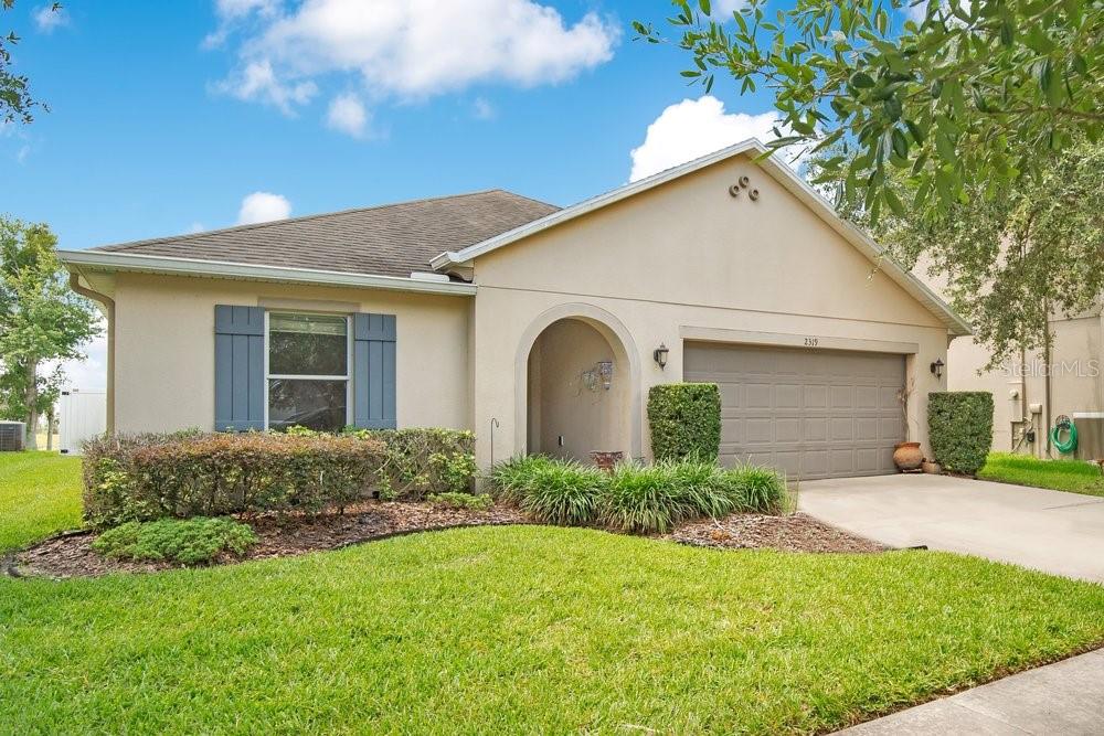 A single-story house with a beige stucco exterior, a two-car garage, and a front lawn — 2319 PLANTATION OAK DRIVE, ORLANDO, FL
