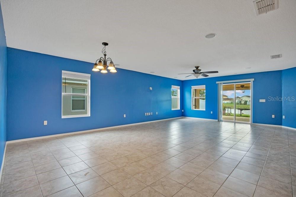 A spacious living room features bright blue walls, tile flooring, a chandelier, and sliding doors — 2319 PLANTATION OAK DRIVE, ORLANDO, FL