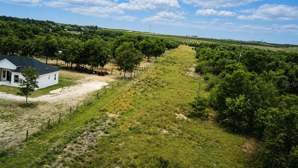 An aerial view shows a white house next to a large, grassy field and trees — 1716 TINDEL CAMP ROAD, LAKE WALES, FL