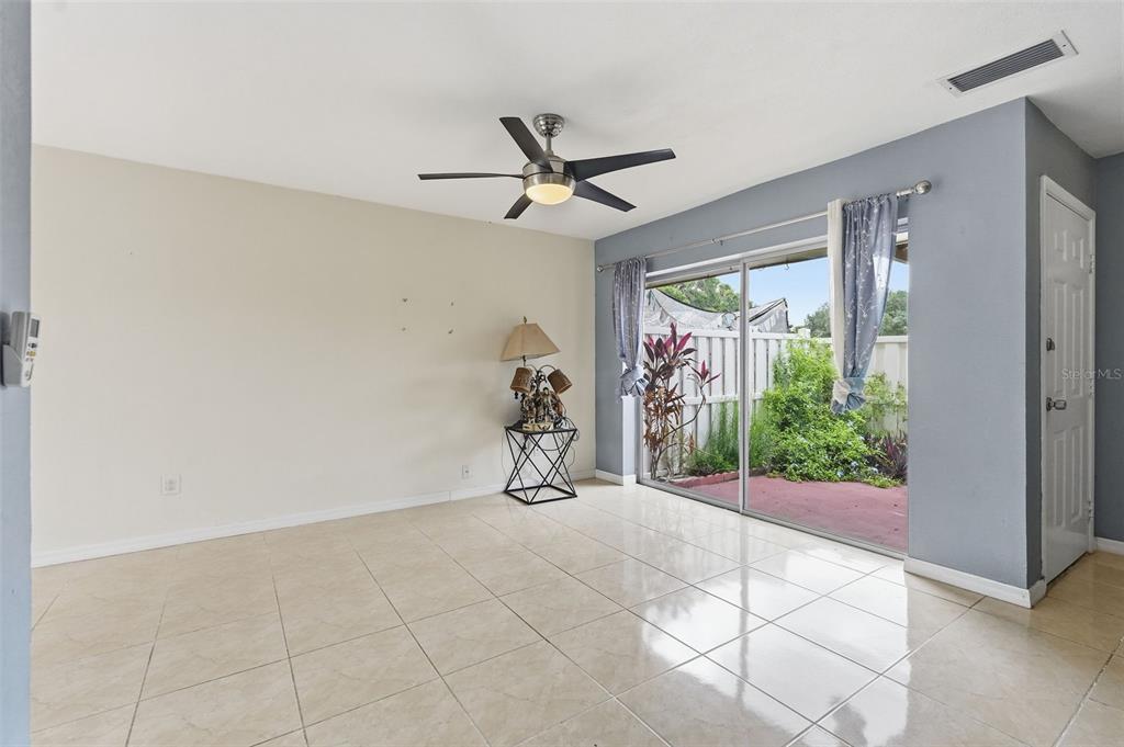An empty room with tile floors, a ceiling fan, and sliding glass doors to a patio — 6902 EL CENTRO COURT, TAMPA, FL