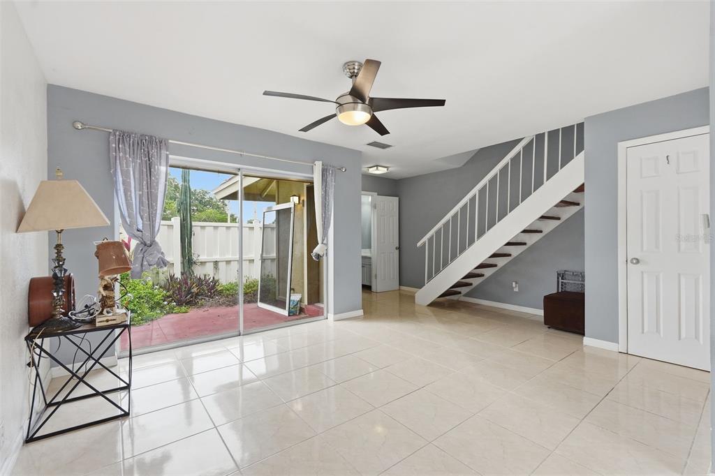 A living room features light tile floors, a staircase, and sliding glass doors to a patio — 6902 EL CENTRO COURT, TAMPA, FL