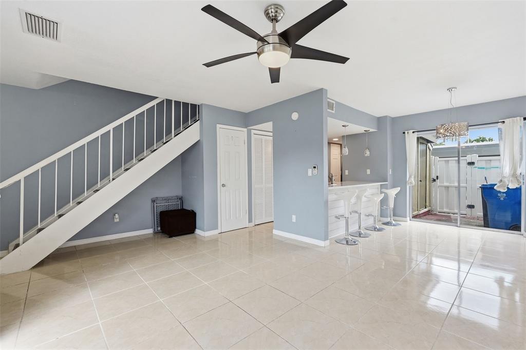 A living room with light tile floors, a staircase, and a breakfast bar with stools — 6902 EL CENTRO COURT, TAMPA, FL