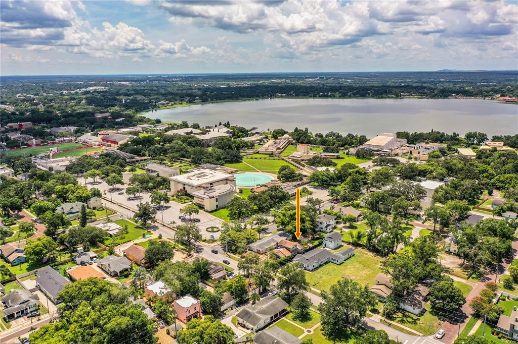 An aerial view shows a residential property marked by an arrow near a large lake — 721 FRANK LLOYD WRIGHT WAY, LAKELAND, FL