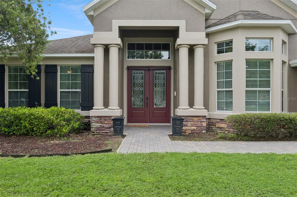 The exterior of a house features a stone-accented entryway with double doors and decorative columns — 2226 PARKSIDE MEADOW DRIVE, APOPKA, FL