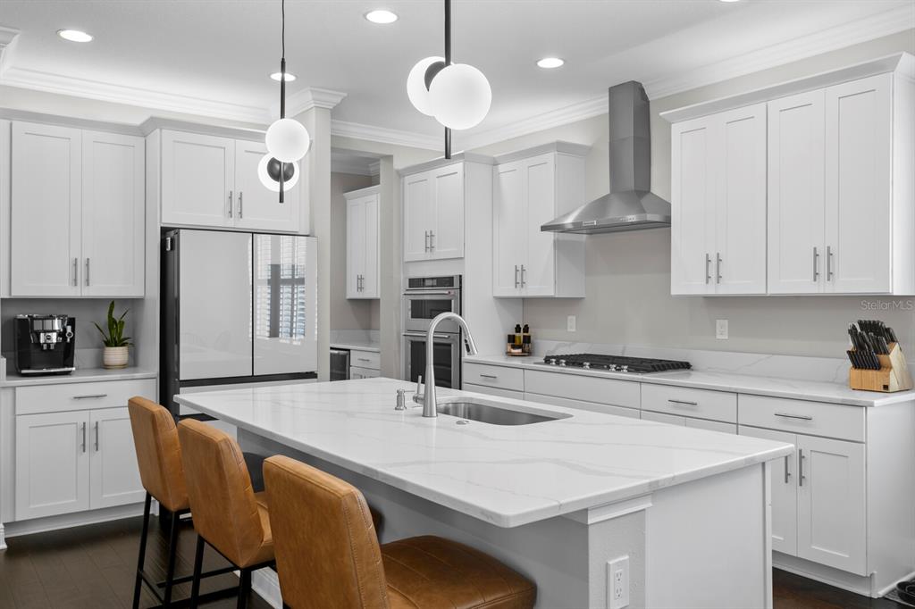 A modern kitchen features white cabinetry, a large marble island, and tan leather bar stools — 2702 W CASS STREET, TAMPA, FL