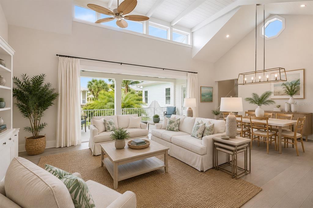 A bright, open-concept living and dining area features vaulted ceilings, white furniture, and a balcony — 16526 CUP COURT, PORT CHARLOTTE, FL