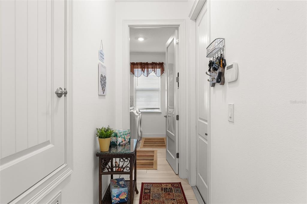 A hallway leads to a laundry room with a small table and wall-mounted key rack — 700 S FLORIDA AVENUE, HOWEY IN THE HILLS, FL