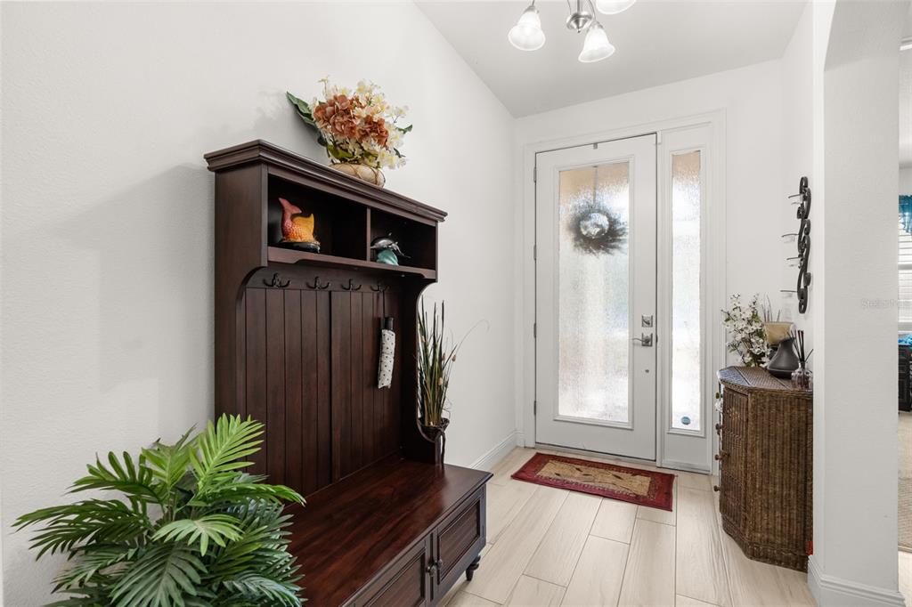 An entryway features a dark wood hall tree, a white front door, and tiled flooring — 700 S FLORIDA AVENUE, HOWEY IN THE HILLS, FL