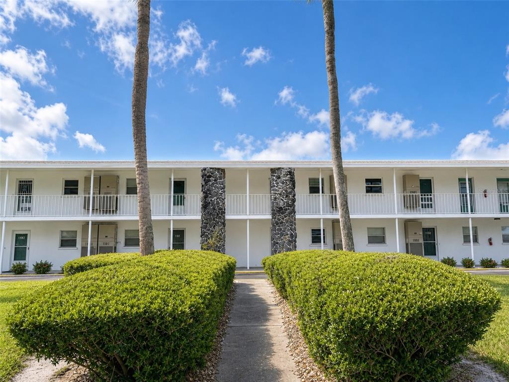 A two-story apartment building exterior features white walls, a balcony, and two palm trees — 3900 ROXANE BOULEVARD UNIT 11B, SARASOTA, FL