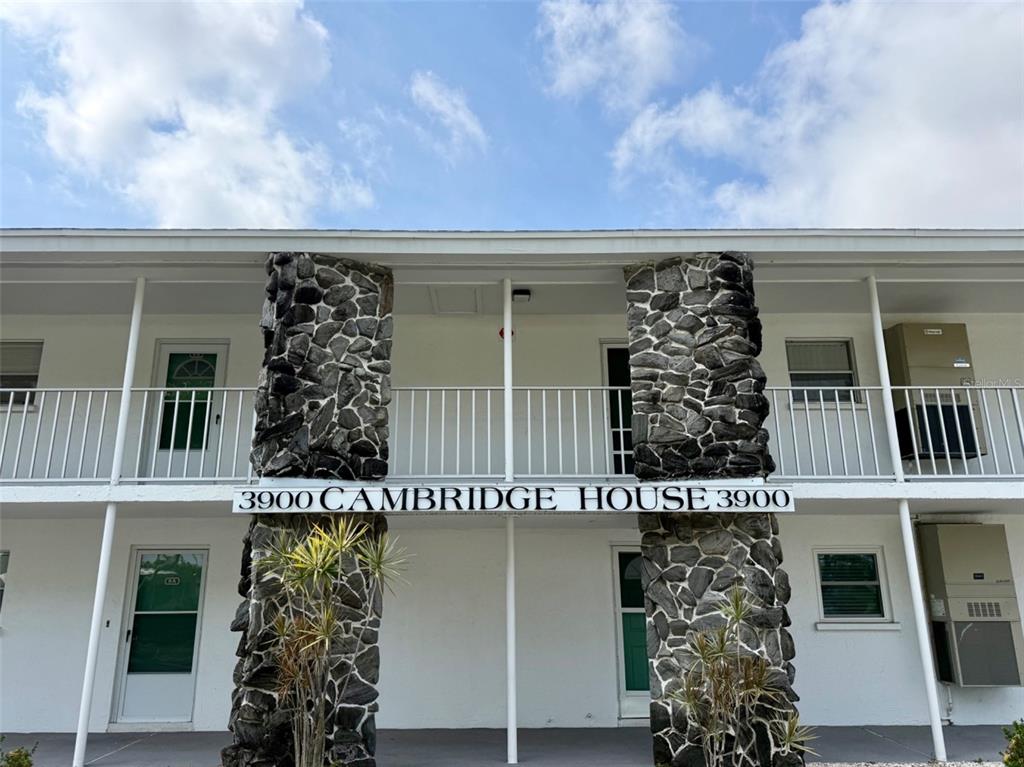 The exterior of a two-story apartment building features stone pillars and a white balcony railing — 3900 ROXANE BOULEVARD UNIT 11B, SARASOTA, FL