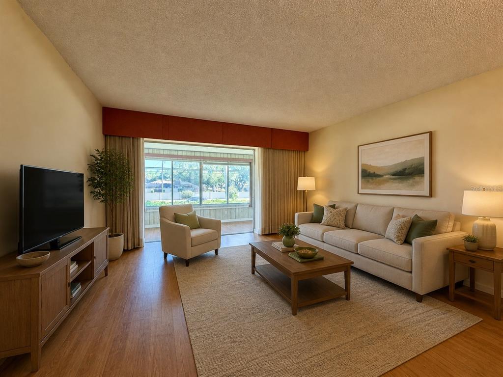 A living room with wood flooring, a beige sofa, a coffee table, and a television — 3900 ROXANE BOULEVARD UNIT 11B, SARASOTA, FL
