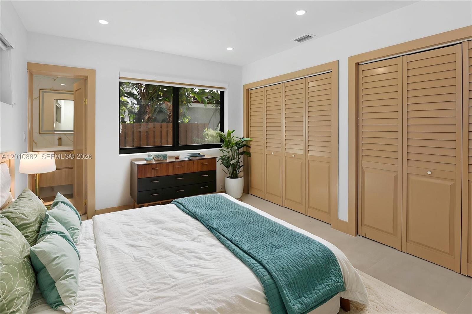 A bedroom features a bed, a dresser, louvered closet doors, and an attached bathroom — 1620 Mckinley St, Hollywood FL 33020, HOLLYWOOD, FL