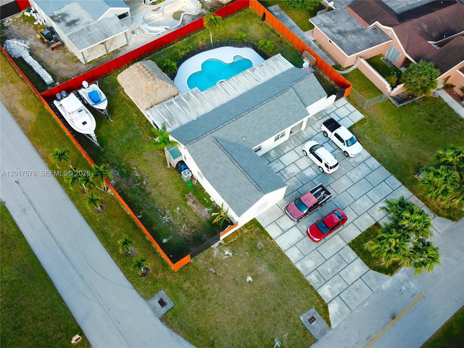 A single-story house with a gray exterior, a garage, and a large paved driveway — 15481 SW 155th Ter, Miami FL 33187, MIAMI, FL