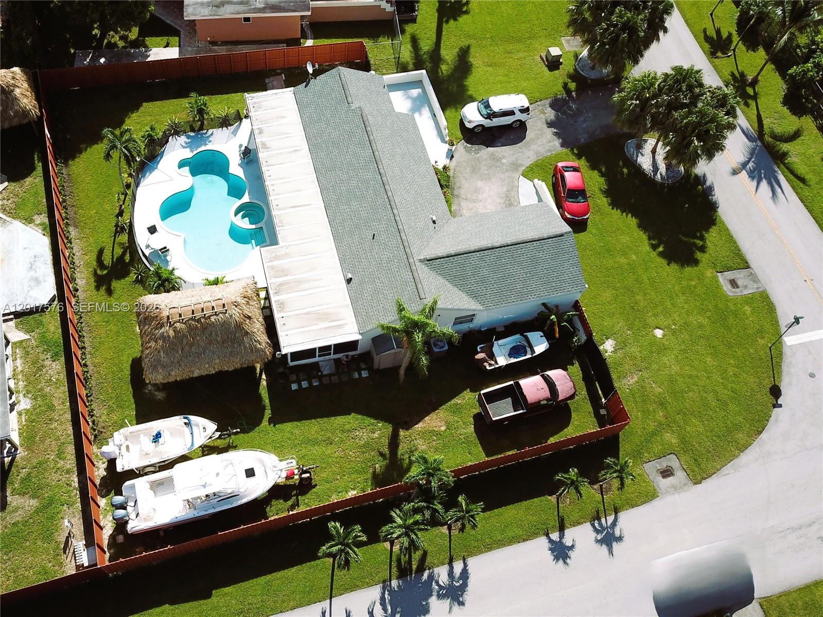 A single-story gray house features a large concrete paver driveway and a wooden fence — 15481 SW 155th Ter, Miami FL 33187, MIAMI, FL