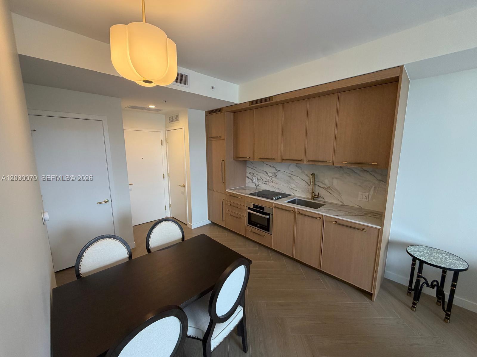 A kitchen with light wood cabinetry, marble backsplash, and a dining area with four chairs — 2700 NW 2nd Ave # 606, Miami FL 33127, MIAMI, FL