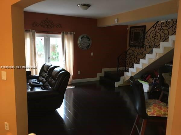A living room features dark hardwood floors, a leather sofa, and a staircase with iron railings — 8067 NW 199th Ter, Hialeah FL 33015, HIALEAH, FL