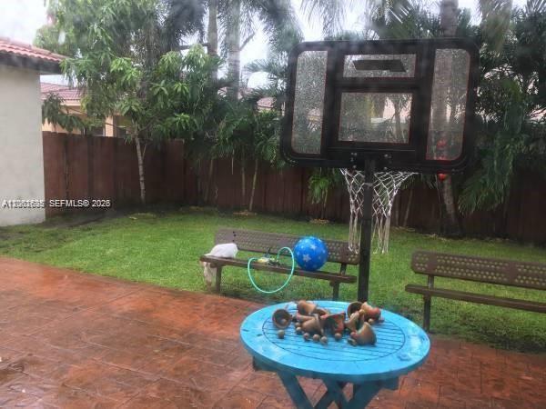 A backyard patio features a blue table, a basketball hoop, and two wooden benches — 8067 NW 199th Ter, Hialeah FL 33015, HIALEAH, FL