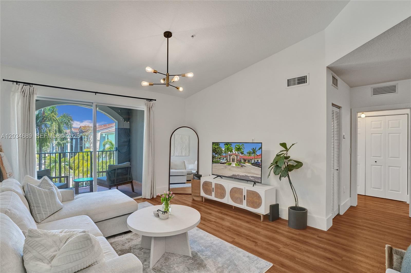 A living room features a white sofa, round coffee table, media console, and balcony access — 6841 SW 44th St # 305, Miami FL 33155, MIAMI, FL