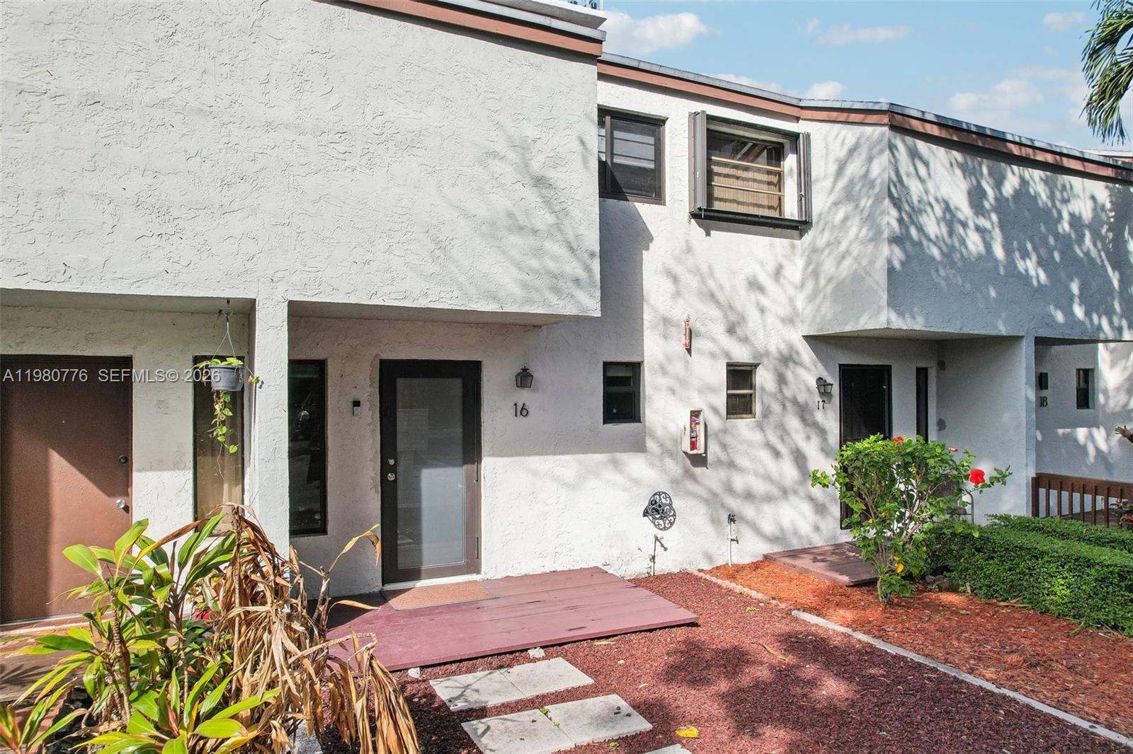 The exterior of a multi-unit residential building features stucco walls, numbered doors, and small decks — 1901 NW S River Dr # 16B, Miami FL 33125, MIAMI, FL