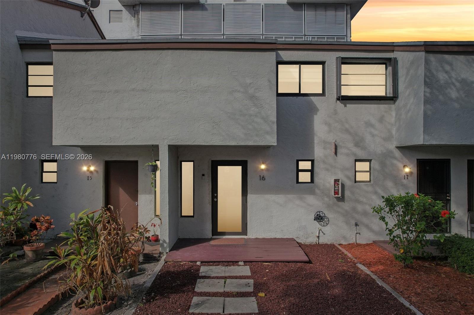 The exterior of a multi-unit residential building features gray stucco walls and a wooden entryway — 1901 NW S River Dr # 16B, Miami FL 33125, MIAMI, FL