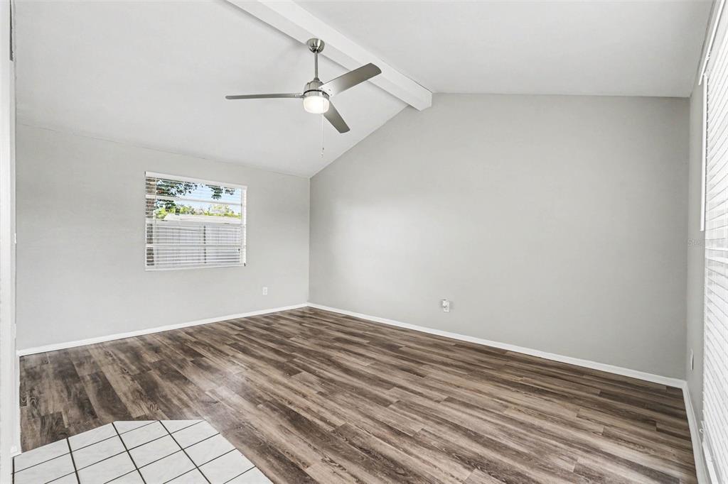 An empty room with light gray walls, wood-look flooring, and a vaulted ceiling with fan — 6404 FREEDOM COURT, TAMPA, FL