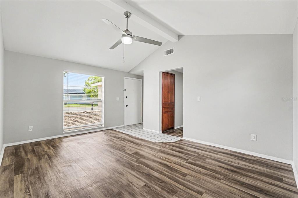 A living room features wood-look flooring, a vaulted ceiling with a fan, and a tiled entryway — 6404 FREEDOM COURT, TAMPA, FL
