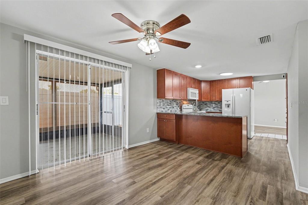 A kitchen and dining area with wood-look flooring, wood cabinets, and a sliding glass door — 6404 FREEDOM COURT, TAMPA, FL