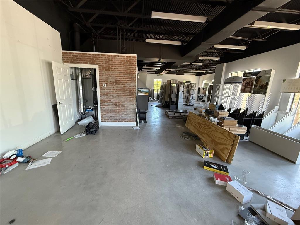 An unfinished commercial space features a brick accent wall, exposed ceiling, and concrete flooring — 5920 PAN AMERICAN BOULEVARD UNIT 104, NORTH PORT, FL