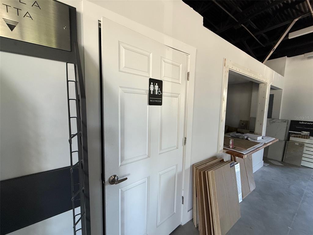 A white door with a restroom sign is situated in a room with construction materials — 5920 PAN AMERICAN BOULEVARD UNIT 104, NORTH PORT, FL