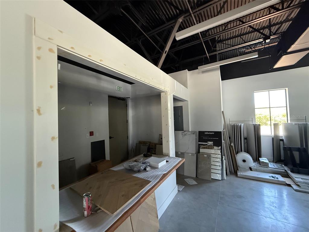 An unfinished interior space features a wooden service counter and stacks of tile samples — 5920 PAN AMERICAN BOULEVARD UNIT 104, NORTH PORT, FL