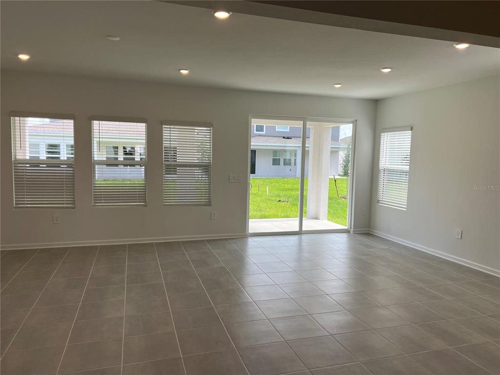An empty room with light-colored tile flooring, recessed lighting, and a sliding glass door — 5511 NINA WAY, ST CLOUD, FL