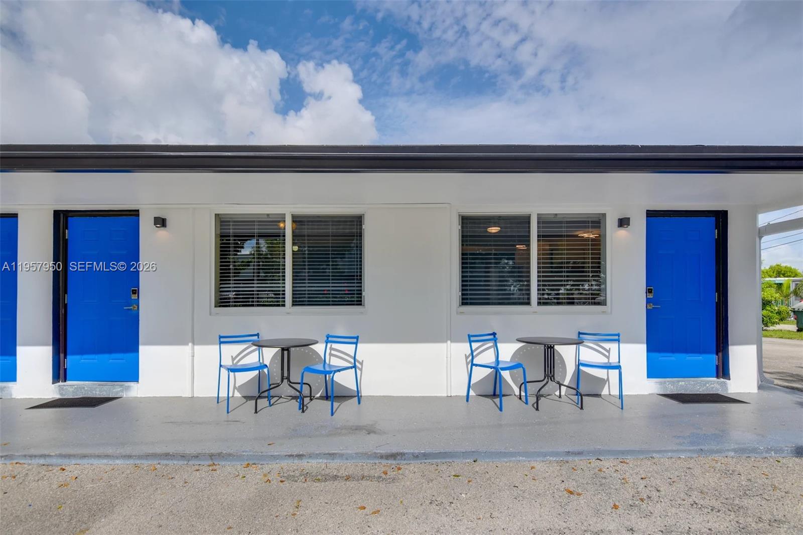 A building exterior features two blue doors, two windows, and two sets of outdoor furniture — 412 NE 4th Ave, Hallandale Beach FL 33009, HALLANDALE BEACH, FL