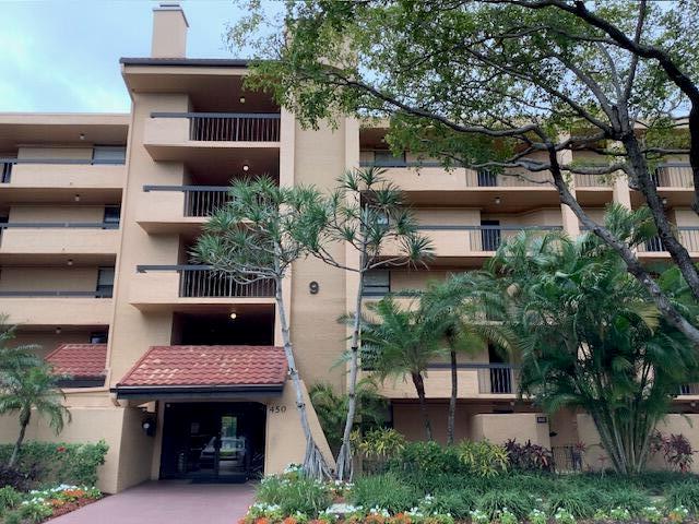 A multi-story tan apartment building features balconies, a tiled entryway, and surrounding tropical landscaping — 450 Egret Circle # 9209, Delray Beach FL 33444, DELRAY BEACH, FL