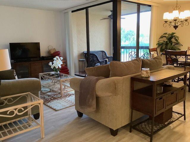 A living room features a beige sofa, a coffee table, and a sliding glass balcony door — 450 Egret Circle # 9209, Delray Beach FL 33444, DELRAY BEACH, FL