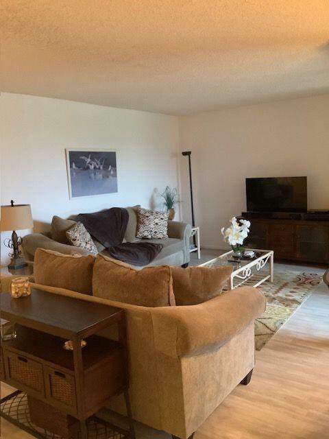 A living room features a beige sofa, a wooden console table, and a television on a stand — 450 Egret Circle # 9209, Delray Beach FL 33444, DELRAY BEACH, FL