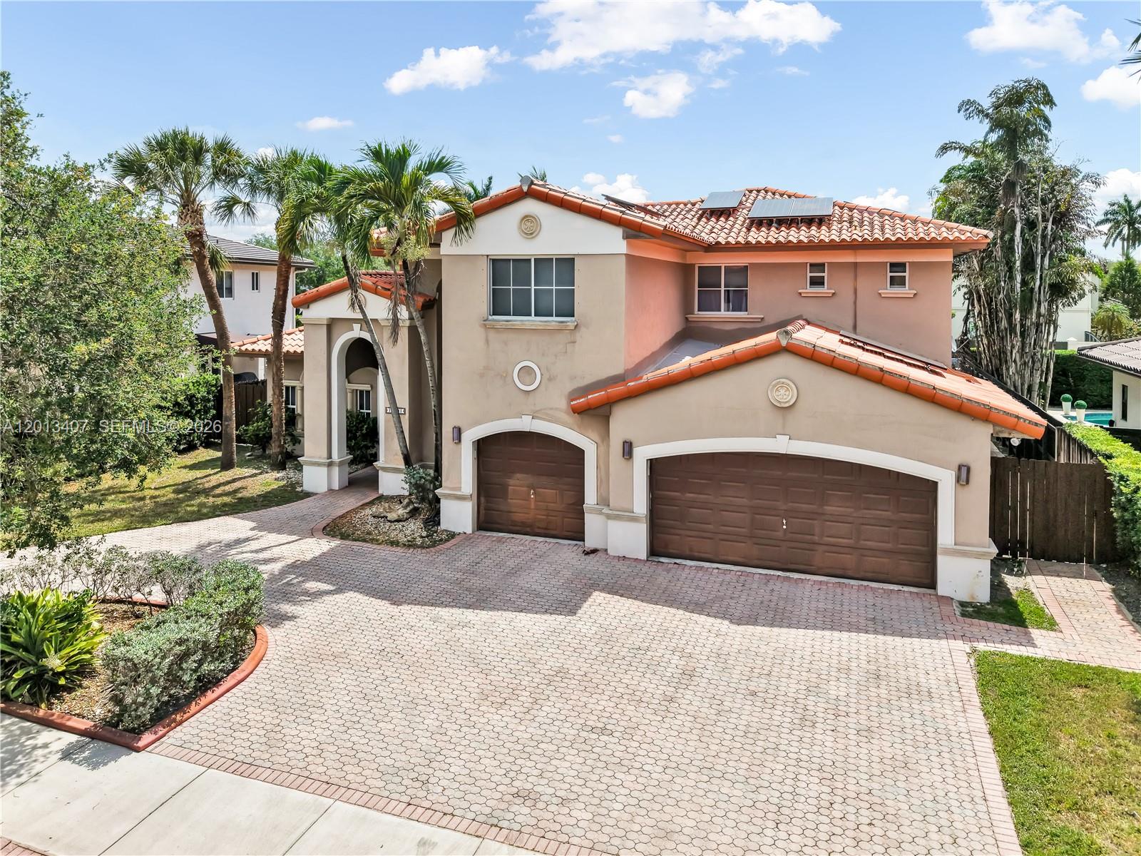 A two-story stucco house with a tiled roof, three garage doors, and a paved driveway — 16101 NW 79th Ct, Miami Lakes FL 33016, MIAMI LAKES, FL