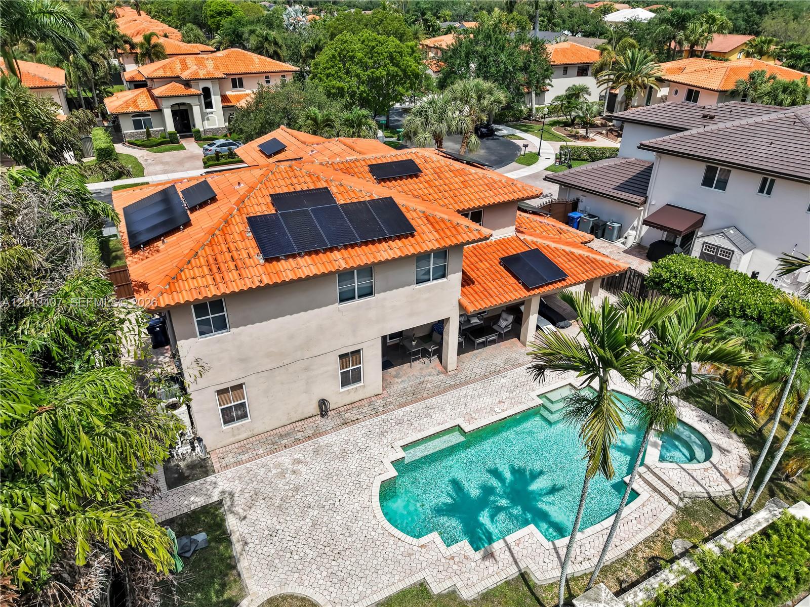 An aerial view shows a two-story house with a tiled roof, solar panels, and pool — 16101 NW 79th Ct, Miami Lakes FL 33016, MIAMI LAKES, FL