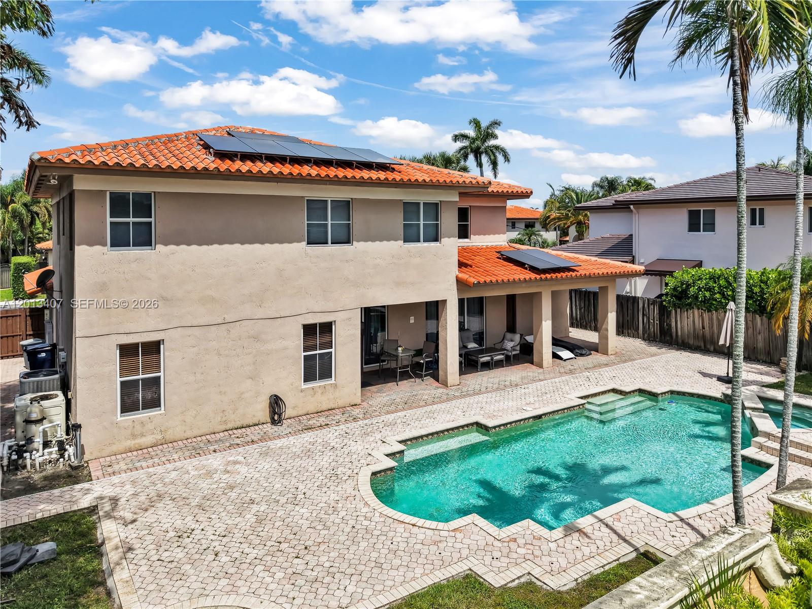 The exterior of a two-story house features a tiled roof, solar panels, and a pool — 16101 NW 79th Ct, Miami Lakes FL 33016, MIAMI LAKES, FL