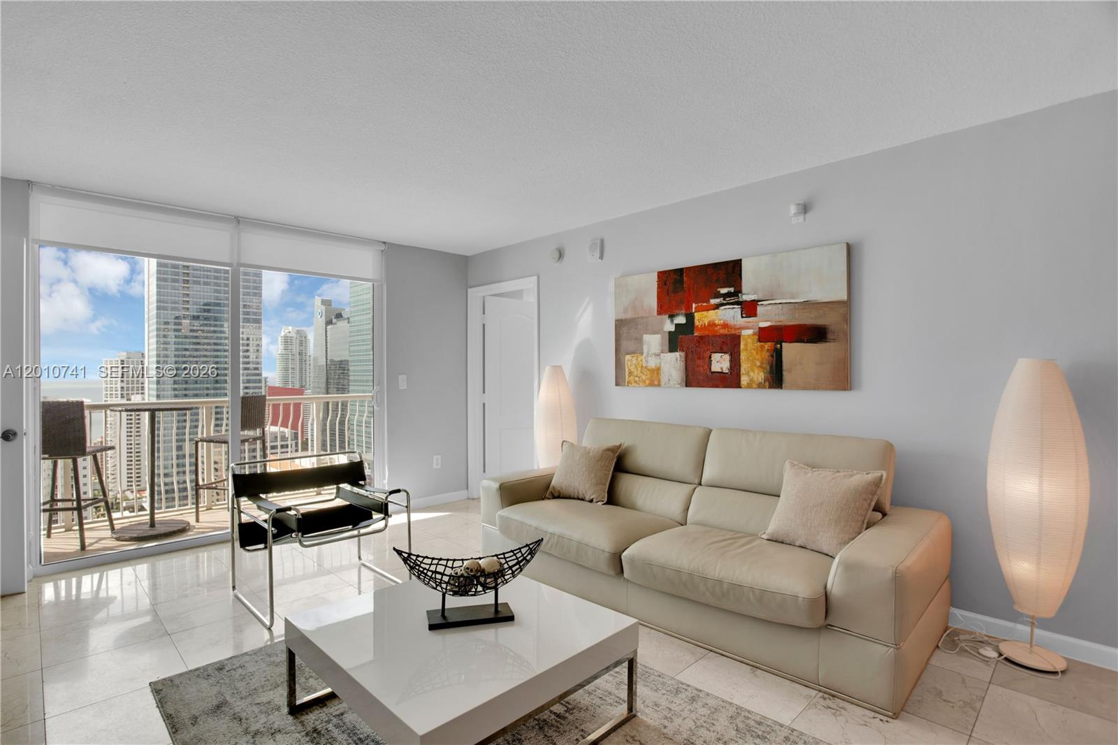 A living room features a beige sofa, a white coffee table, and a balcony view — 1200 Brickell Bay Dr # 3515, Miami FL 33131, MIAMI, FL