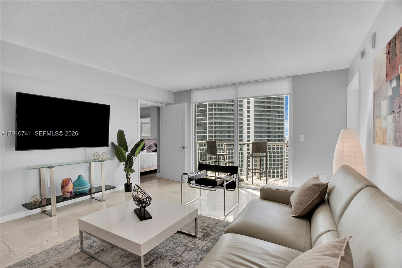 A modern living room features a white sofa, glass console table, and a balcony view — 1200 Brickell Bay Dr # 3515, Miami FL 33131, MIAMI, FL