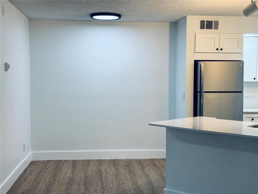 A dining area features a blank wall, a flush-mount light fixture, and wood-look flooring — 4630 COMMANDER DRIVE UNIT 1023, ORLANDO, FL