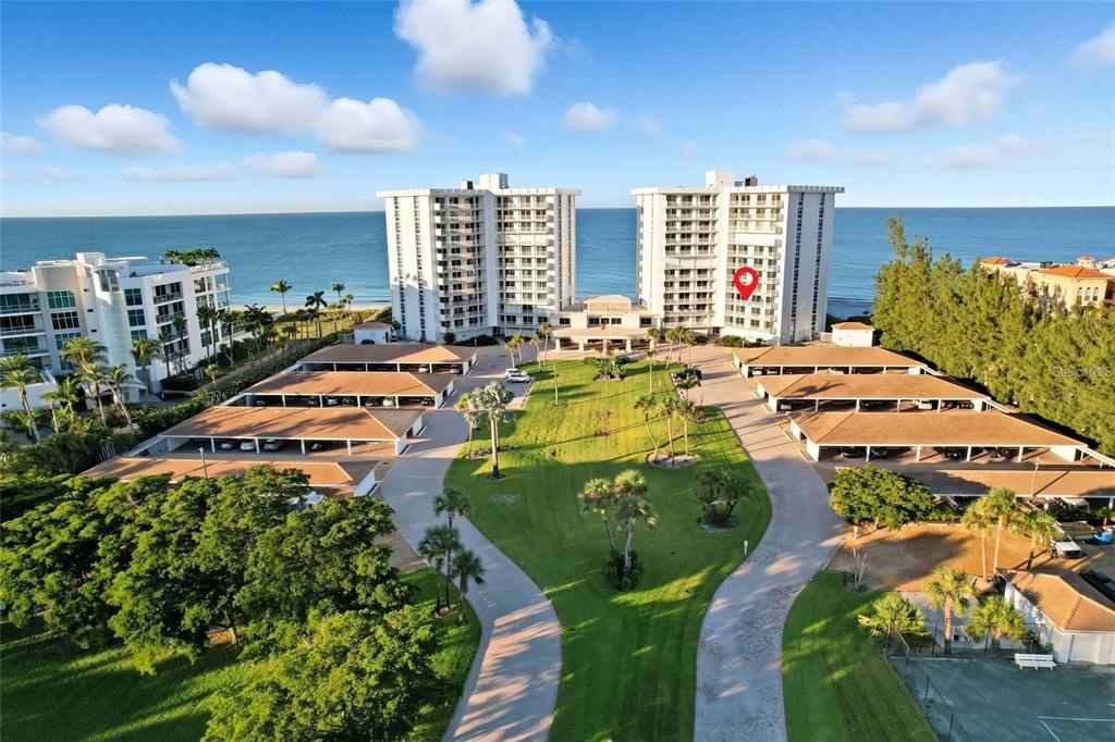 An aerial view shows two tall residential buildings situated on a beach with parking structures — 2301 GULF OF MEXICO DRIVE UNIT 45N, LONGBOAT KEY, FL