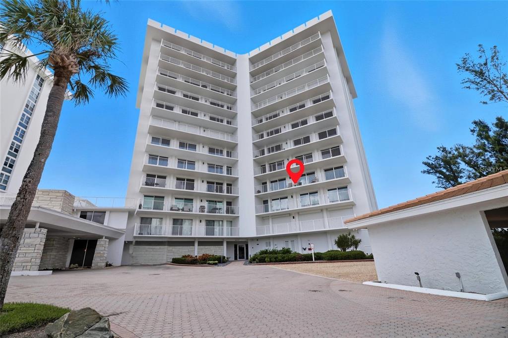 A tall white residential building with balconies features a red location pin on one unit — 2301 GULF OF MEXICO DRIVE UNIT 45N, LONGBOAT KEY, FL