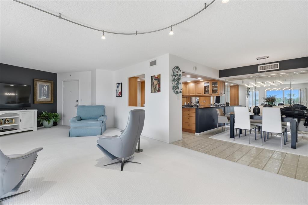 A living room with white carpet, a blue armchair, and an adjacent dining area — 2301 GULF OF MEXICO DRIVE UNIT 45N, LONGBOAT KEY, FL