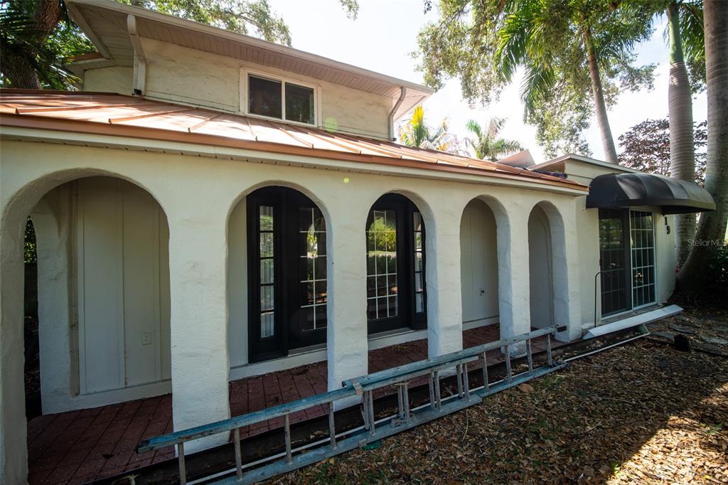 The exterior of a house features a covered porch with arched columns and a metal roof — 219 24 STREET W, BRADENTON, FL