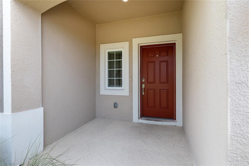 A covered front porch features a red door and a single window with white trim — 5780 HAVEN TERRACE, NOKOMIS, FL
