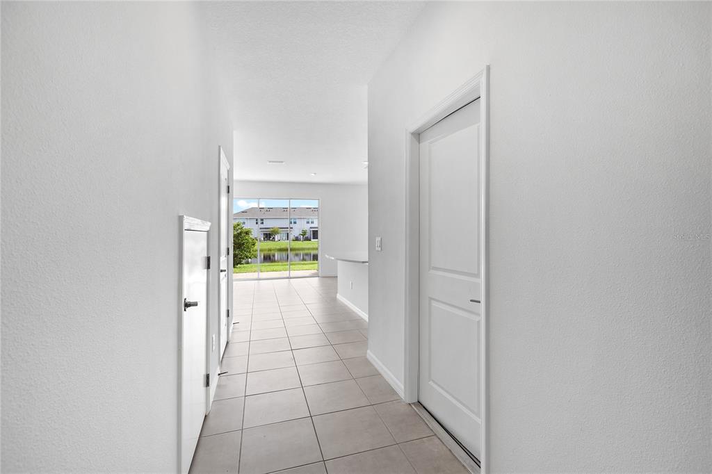 A tiled hallway leads toward a living area with a view of a pond outside — 5780 HAVEN TERRACE, NOKOMIS, FL